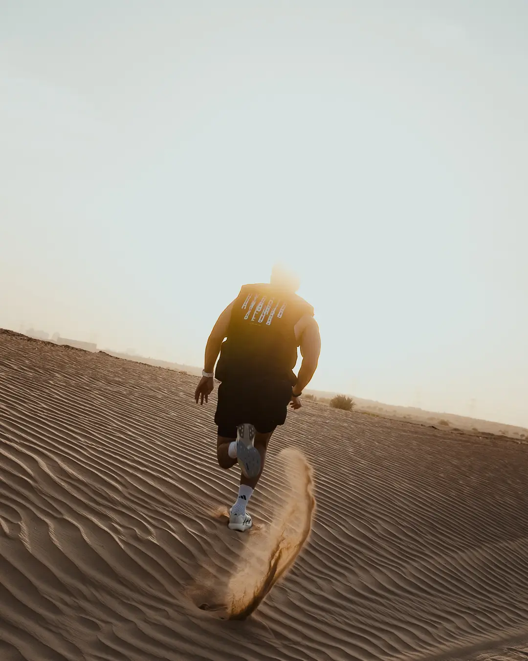 Athlete running up a desert dune in a HYBRID CLUB tee
