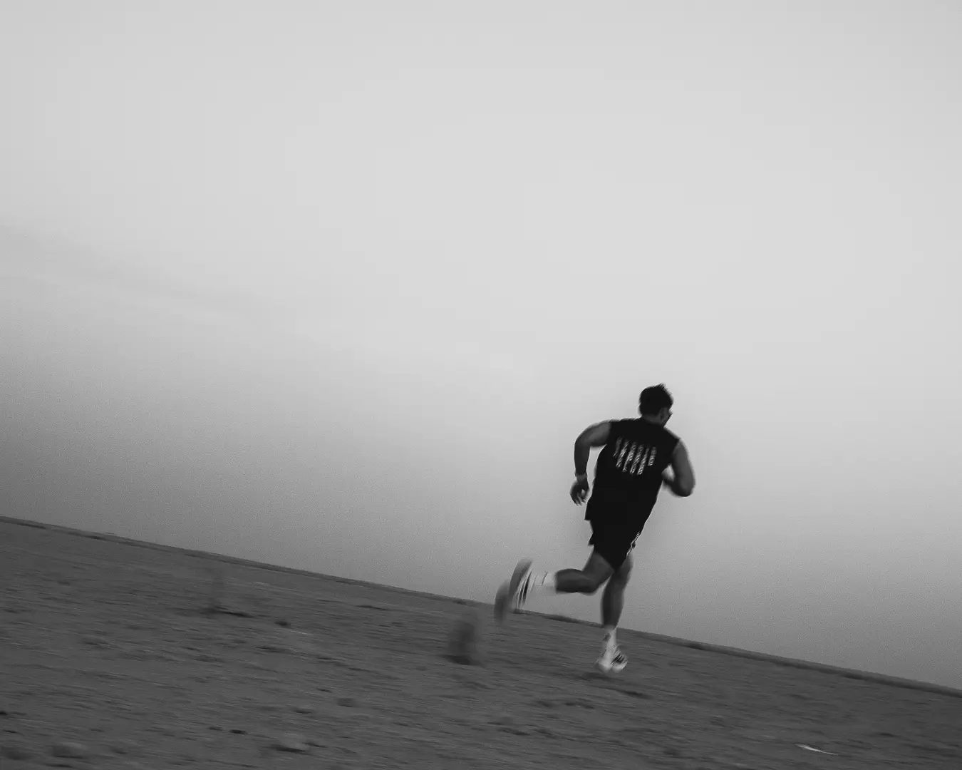 Athlete running on open ground, grayscale
