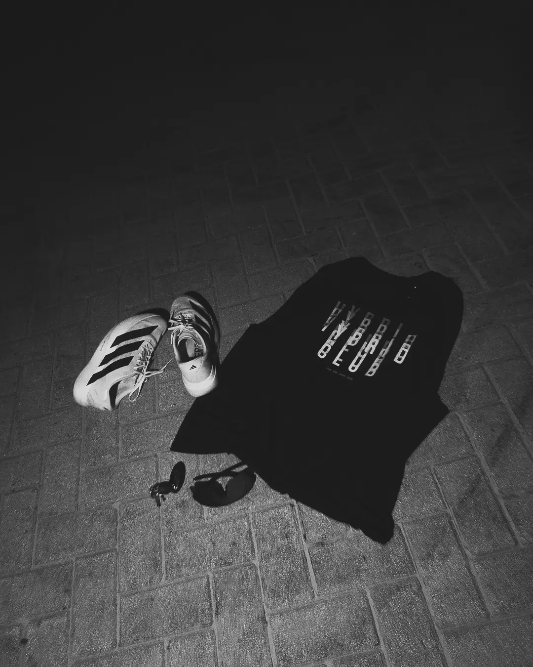 Running shoes, a HUMANCE tee and sunglasses laid out on paving